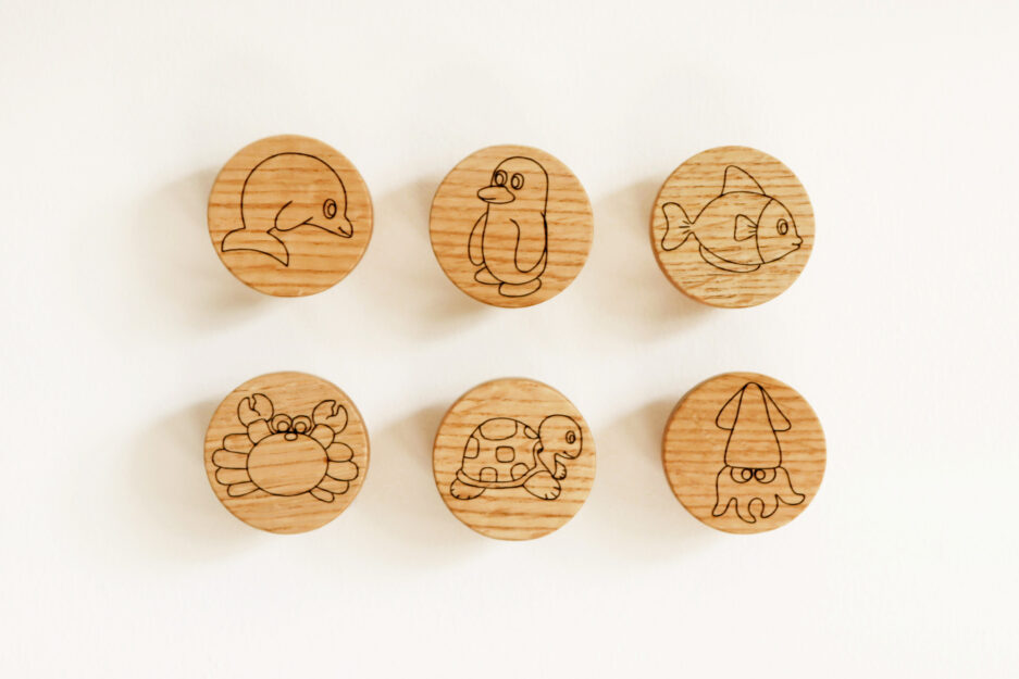 A set of 6 wooden drawer knobs featuring marine animals: dolphin, penguin, fish, crab, turtle, and squid, perfect for a nautical-themed nursery or kids' room.