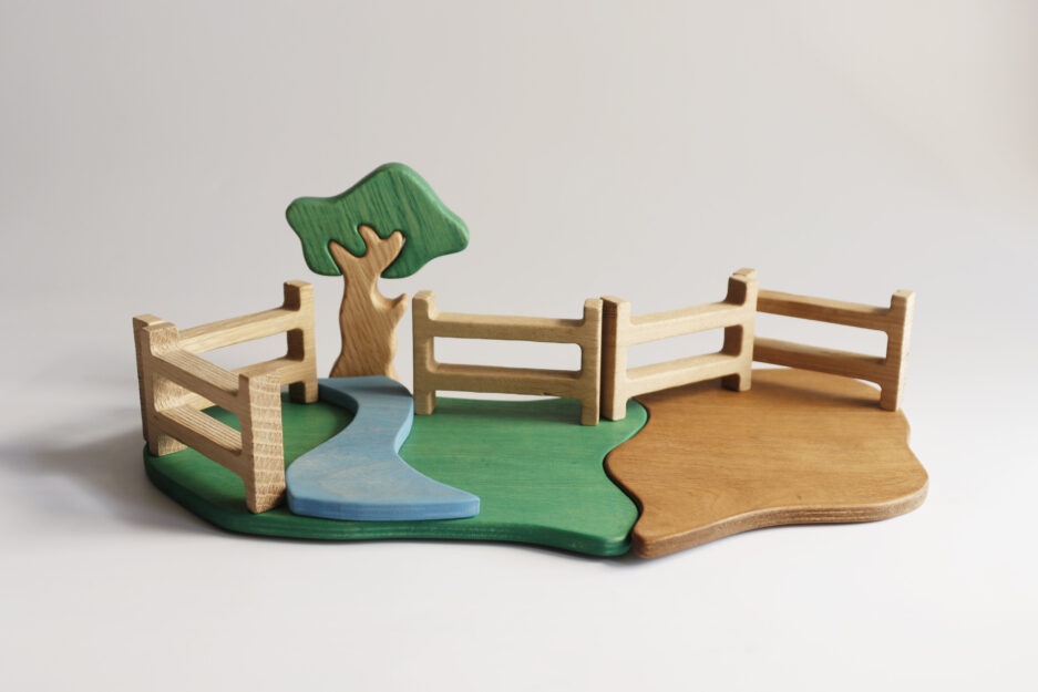 Eco-friendly wooden toy farm scene with trees, a wooden fence, and puzzle-style base pieces