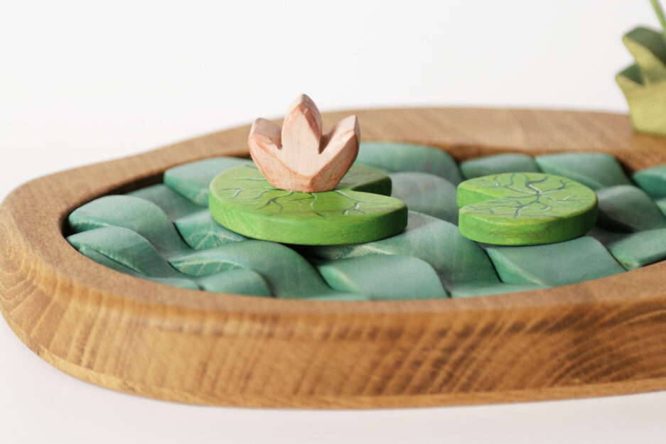 Eco-friendly wooden playset featuring a pond, plants, and a pink lotus flower