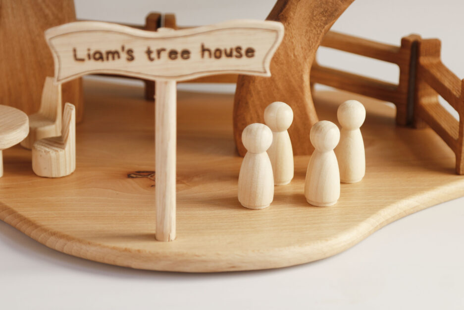 Personalized wooden sign reading 'Liam's tree house' at the base, surrounded by tiny chairs and a table